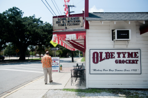 a man standing on a sidewalk next to old tyme grocery in lafayette