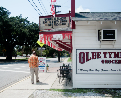 a man standing on a sidewalk next to old tyme grocery in lafayette