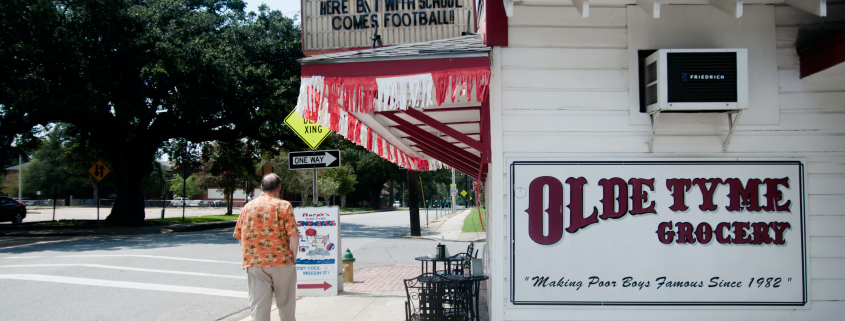 a man standing on a sidewalk next to old tyme grocery in lafayette