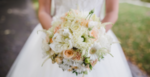 a bride holding a bouquet of white and orange flowers